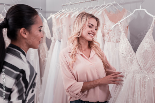 Wedding dress shop. Nice happy women looking at a dress while visiting a wedding boutique
