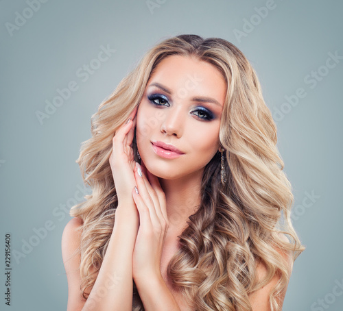 Beautiful blonde woman fashion model with long curly hair and makeup on banner background with copy space