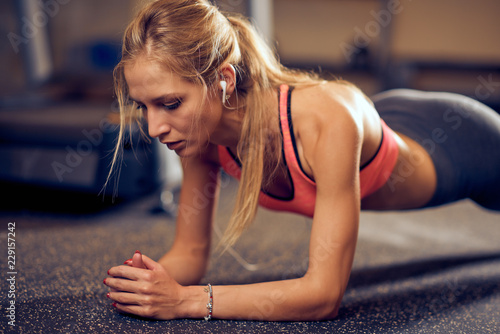 Fototapeta Naklejka Na Ścianę i Meble -  Woman doing planks on gym floor. Healthy lifestyle concept.