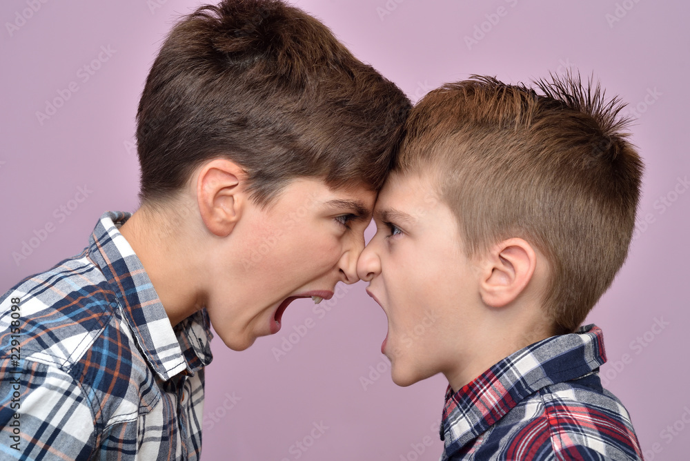 Two angry brothers standing face to face, quarreling, shouting and looking at each other Two angry brothers standing face to face, quarreling, shouting and looking at each other