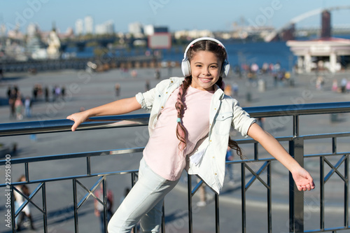 Let the music take you away. Little child listen to music outdoor. Happy little child. Little music fan. Happy girl wear headphones. Beat of the street