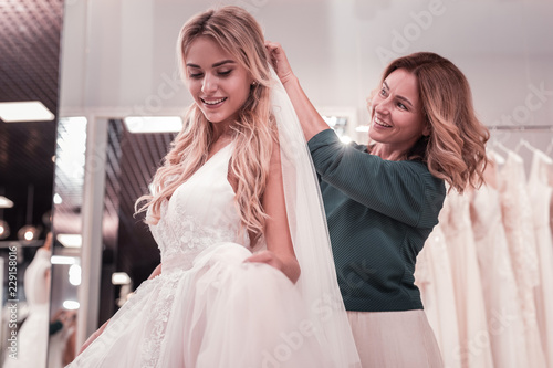 Caring mother. Happy good looking woman smiling while putting a veil on her daughters head photo