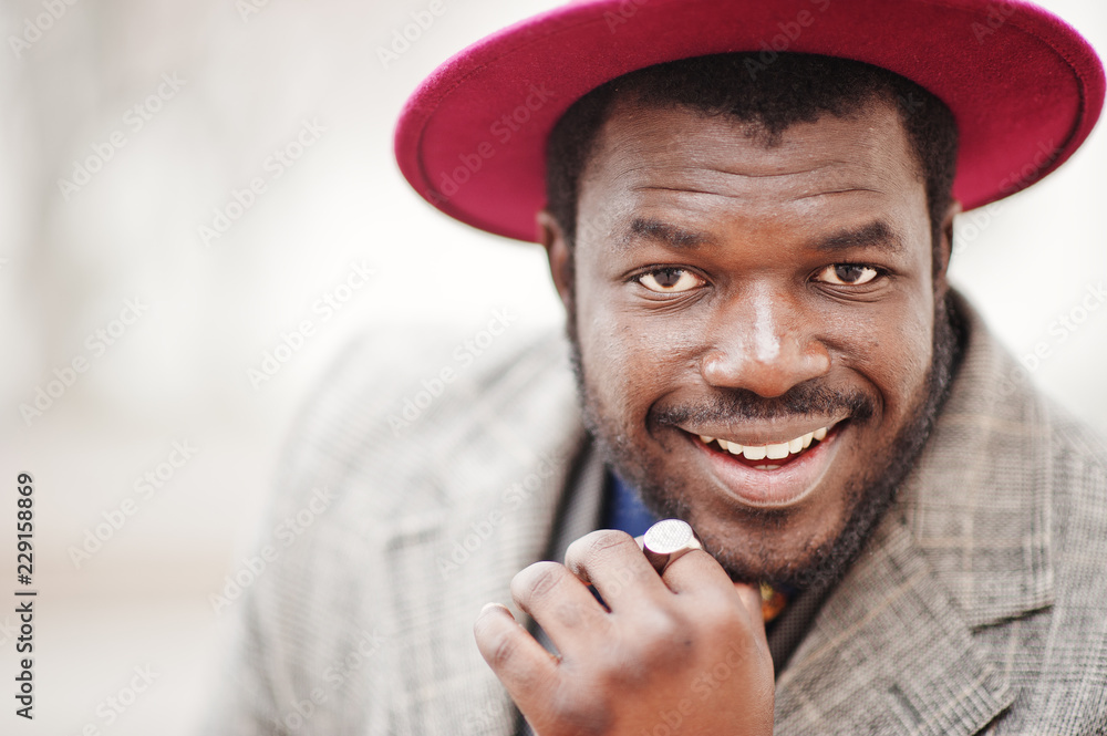 Close up portrait of stylish African American man model in gray coat, jacket tie and red hat. Close up portrait of stylish African American man model in gray coat, jacket tie and red hat.