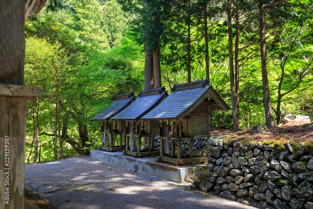 Three small altars next to stone wall at shrine woods