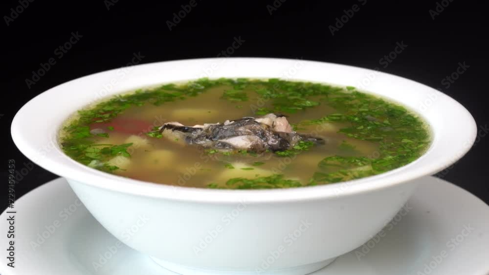 Fish soup with vegetables. Healthy food, fish soup with carrot, pepper, herbs and potato in white plate, close up , rotates Fish soup with vegetables. Healthy food, fish soup with carrot, pepper, herbs and potato in white plate, close up , rotates