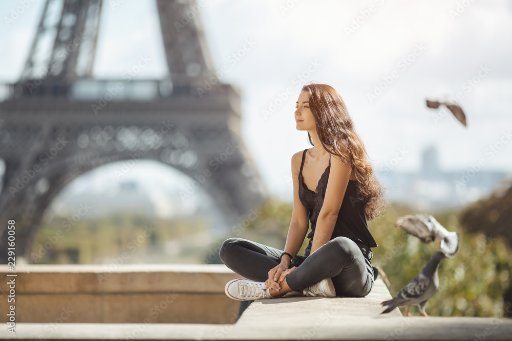 Naklejka premium Szczęśliwa kobieta podróży w pobliżu wieży Eiffla w Paryżu. Dziewczyna turystyczny podróży na wakacje odpoczynek szczęśliwy na świeżym powietrzu. Gołębie symbol miłości latające wokół fliynig Atrakcyjna młoda romantyczna kobieta siedzi przeciwko