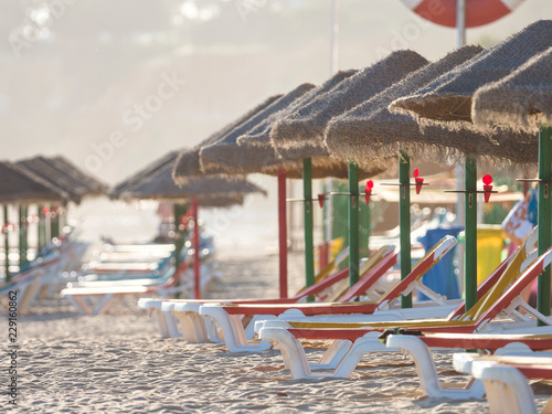 Colorful sun beds under straw umbrellas on the beach