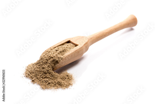 Close-up of pile of ground cardamom spice in a wooden spoon on white background