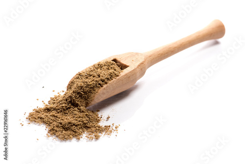 Close-up of pile of ground cumin spice in a wooden spoon on white background