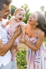 Laughing young family with little baby girl spending time together