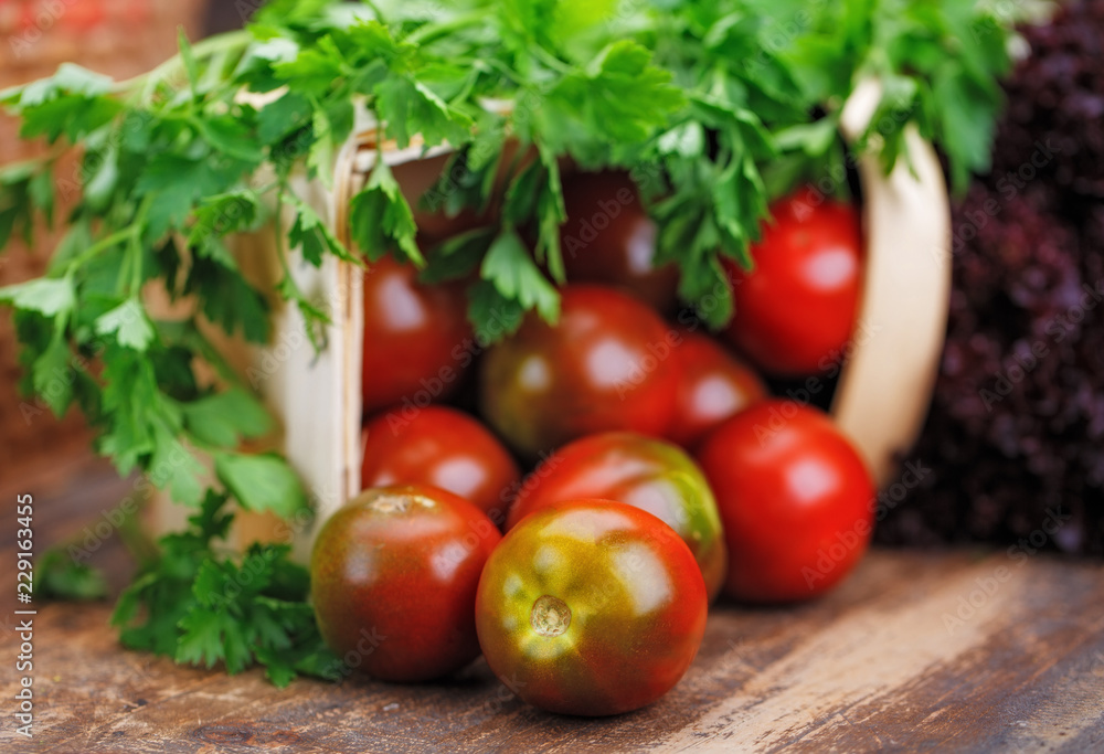 On a wooden table lies basket with tomato, lettuce On a wooden table lies basket with tomato, lettuce
