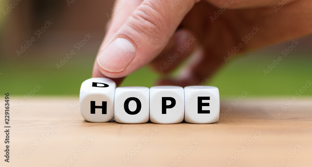 Hand is turning a dice as symbol to have hope instead of dope