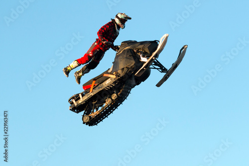 Freestyle motocross rider on snowmobile performs the trick in jump at fmx competitions