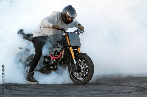 Biker staying on the bike, burning tire and creating smoke on the motorcycle show