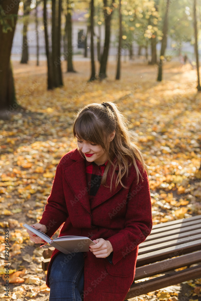 Woman reading volume on bench in park Woman reading volume on bench in park