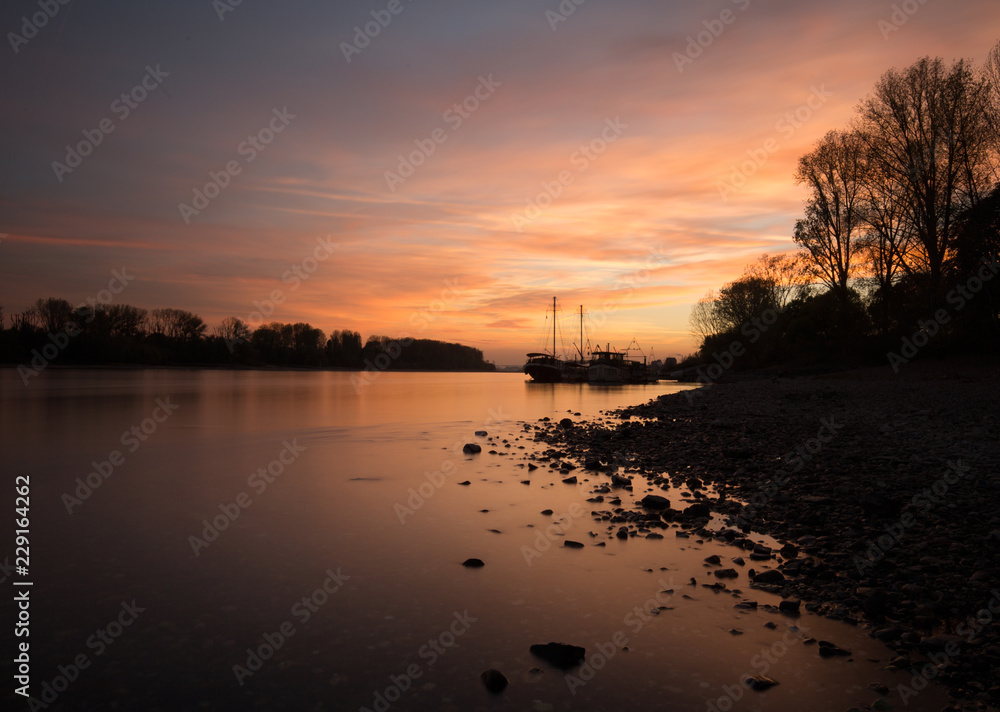Romantic sunset at the shore with two boots floating in the river_2