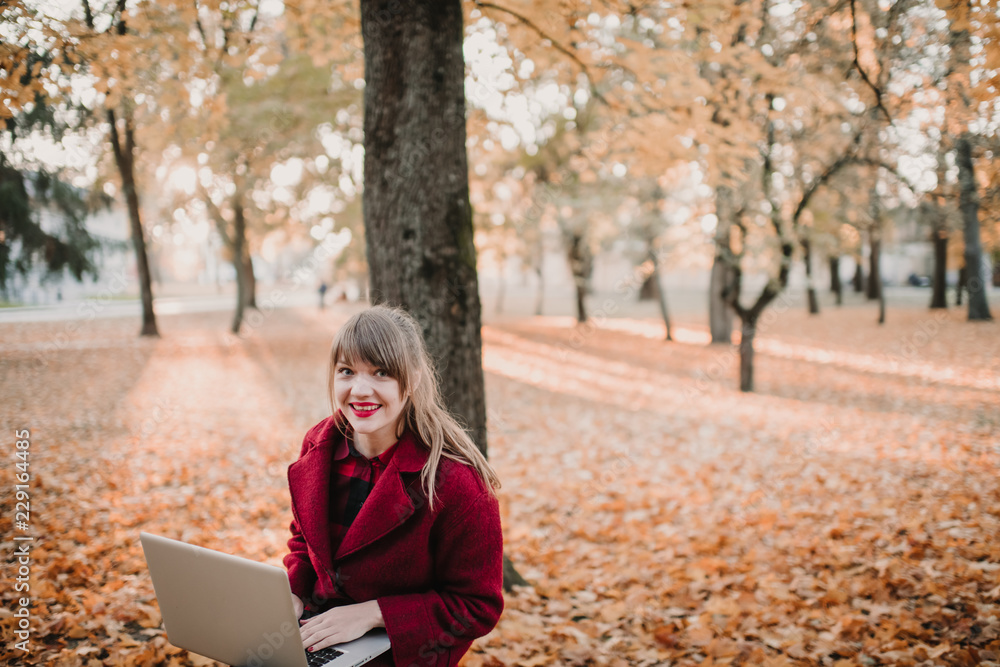 Woman with laptop sitting on bench in park Woman with laptop sitting on bench in park