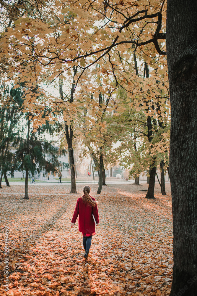 Woman in red coat walking in park Woman in red coat walking in park