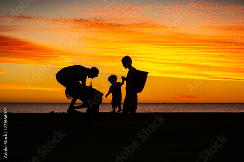 silhouettes of a family with a baby at the beach at sunset