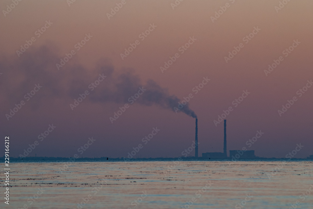 Smoke from the pipe at sunset, Power plant with huge smoke and electric towers in the distance, pollution concept,