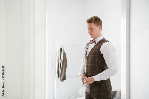 A groom buttoning his waistcoat