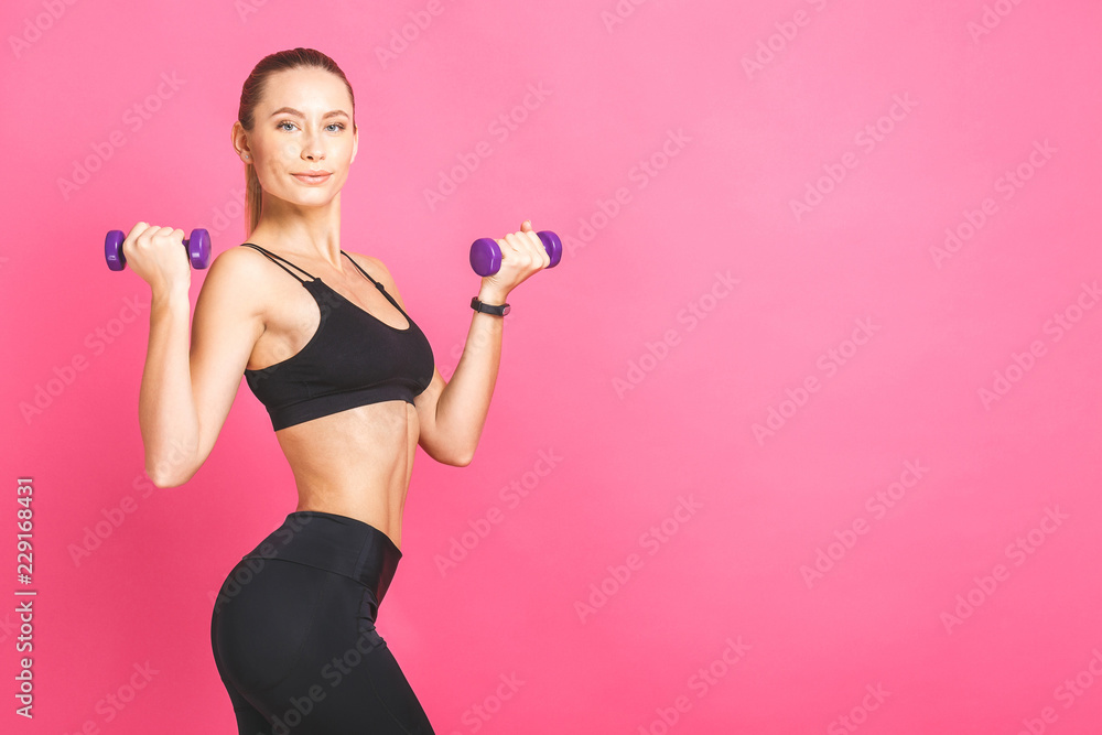 Sporty woman doing exercises with dumbbells. Photo of strong female isolated on white background. Strength and motivation. Isolated over pink. Sporty woman doing exercises with dumbbells. Photo of strong female isolated on white background. Strength and motivation. Isolated over pink.