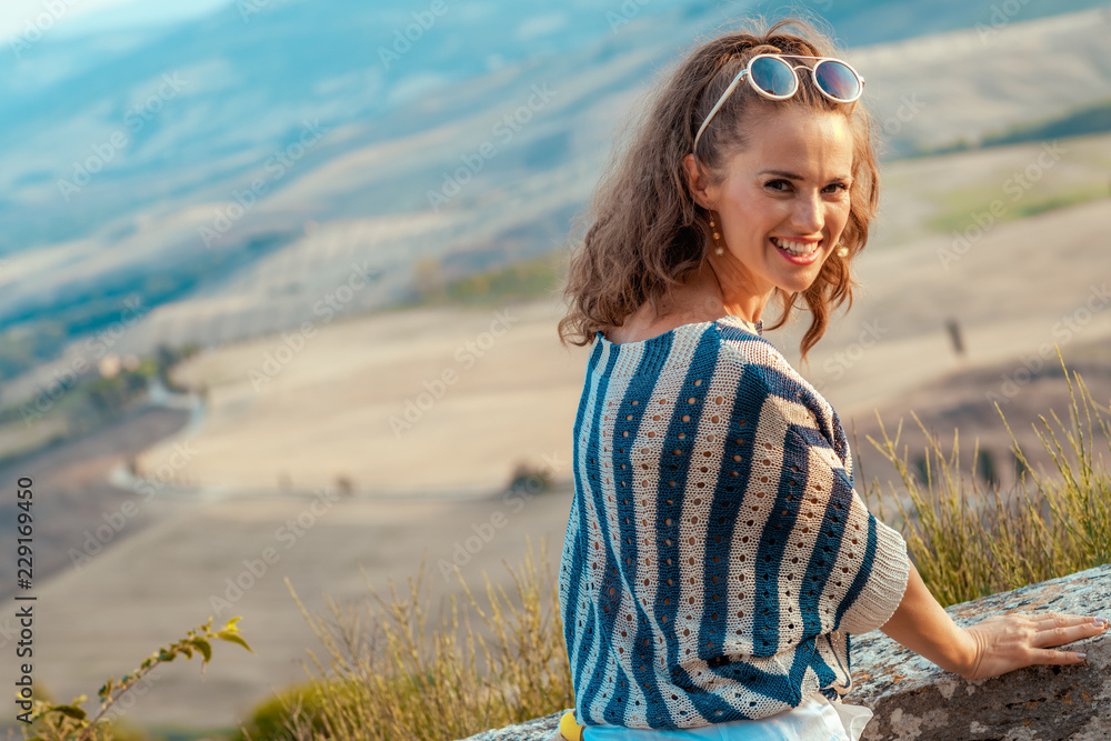 smiling stylish traveller woman in striped blouse in Tuscany
