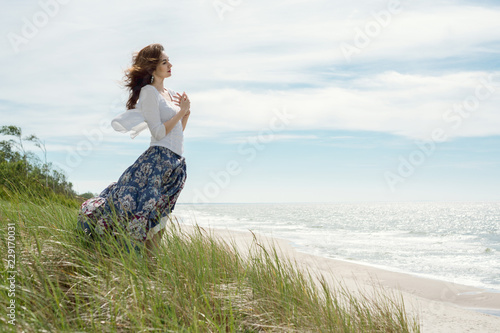 Billede på lærred Young brunette woman in dress stands by the sea