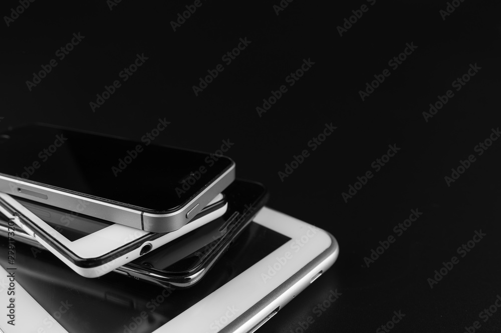 Stack of high-end smartphones on black desk. Stack of high-end smartphones on black desk.