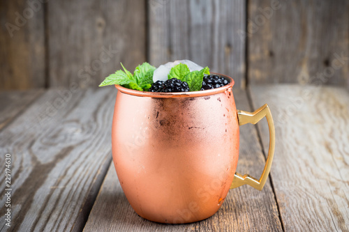 Blackberry moscow mule in copper mug on the rustic background. Selective focus. Shallow depth of field.