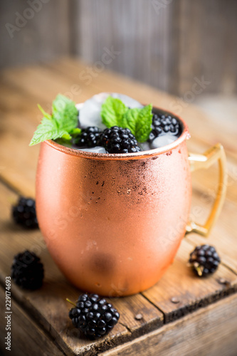 Blackberry moscow mule in copper mug on the rustic background. Selective focus. Shallow depth of field.