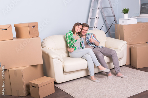Moving and real estate concept - Happy couple kissing on sofa in their new flat
