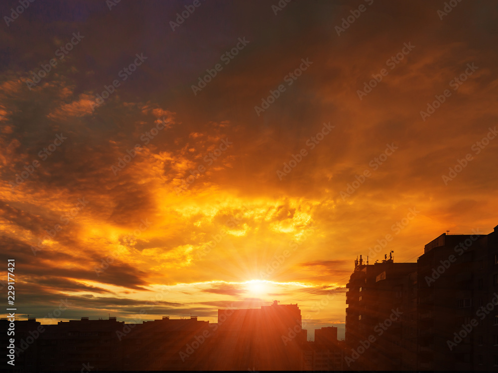 Beautiful orange dawn over city houses, dramatic clouds, background