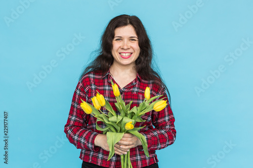 Laughing young caucasian woman with bouquet of tulips on blue background. photo