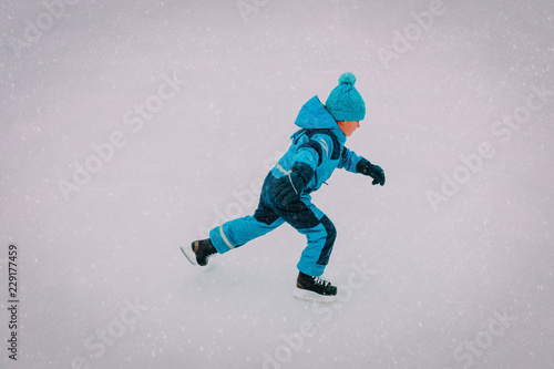 little boy skating on ice in winter