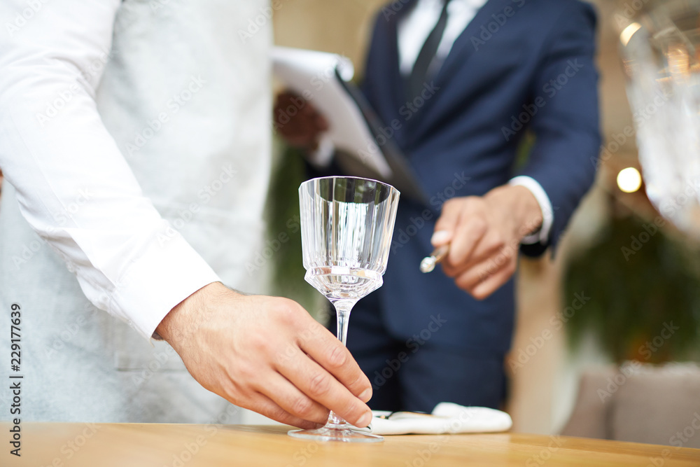 Close-up of waiter puts a wineglass on the table under the supervision of  the restaurant manager Stock Photo | Adobe Stock