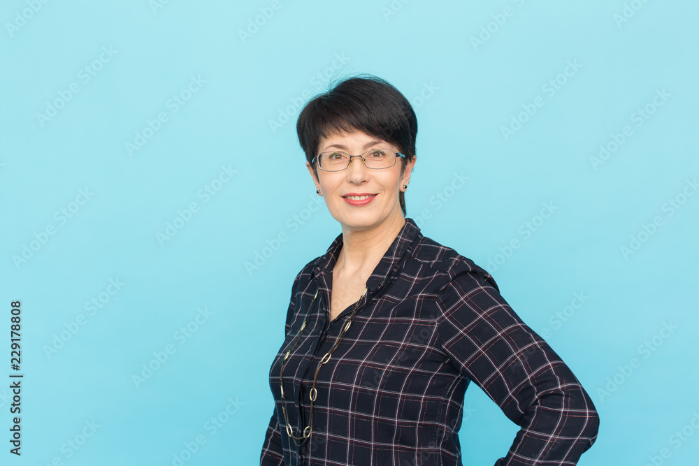 Fashion, people and style concept - Beautiful mid-aged woman wearing eye-glasses laughing on blue background with copy space Fashion, people and style concept - Beautiful mid-aged woman wearing eye-glasses laughing on blue background with copy space