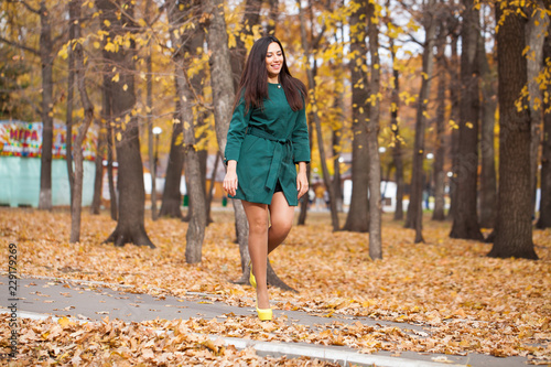 Portrait of a young beautiful brunette woman in short green coat