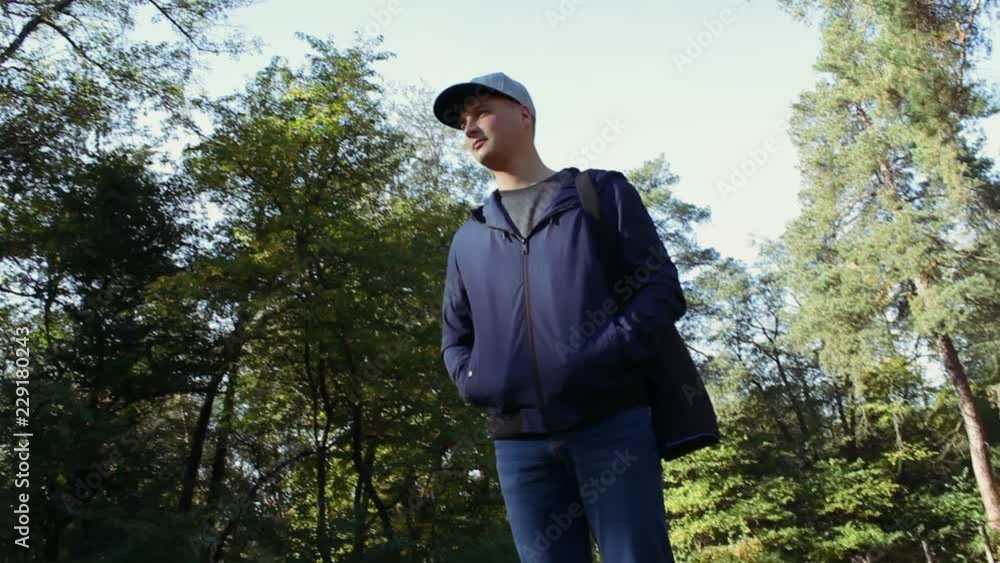 the camera flies around a young man in the park. He is confident in his future, wears a blue clothes the camera flies around a young man in the park. He is confident in his future, wears a blue clothes