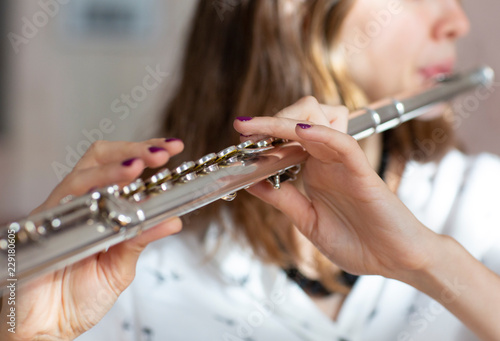 Girl plays on flute. Flute in hands of girl during the concert. Professional musician playing on flute