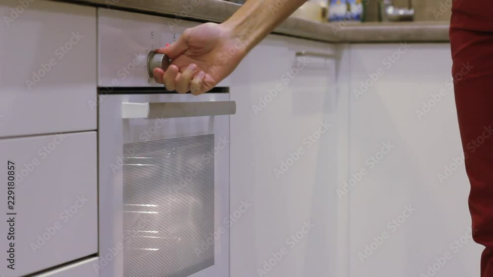 The Man's hand opens white oven on the white kitchen. Minimalism. The Man's hand opens white oven on the white kitchen. Minimalism.
