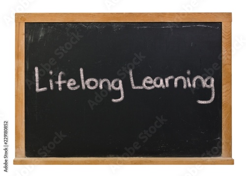 Lifelong learning written in white chalk on a black chalkboard isolated on white