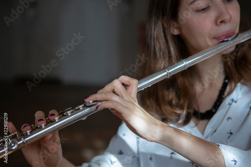 Girl plays on flute. Flute in hands of girl during the concert. Professional musician playing on flute