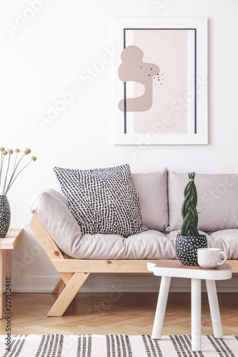 Mock-up painting on a white wall of an artistic living room interior with simple, wooden furniture and patterned decorations