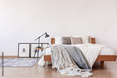 Comfortable king size bed with pillows and blankets in bright bedroom interior with rustic carpet on the floor, real photo with copy space photo