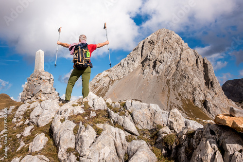 Hiker cheering elated and blissful with arms raised in the sky after hiking to mountain top summit above the clouds. Success concept.