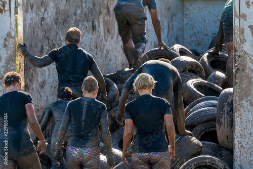 Obraz na plátne Athletes climbing over car tires at an obstacle course race