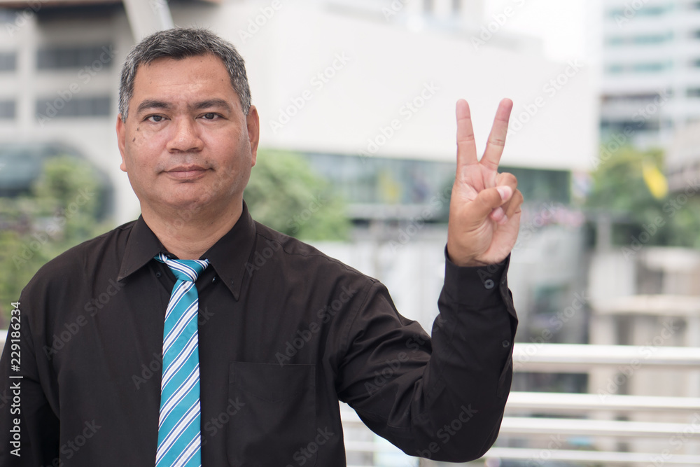 happy old man pointing up victory two fingers; retired pensioner counting, numbering with finger point; senior old man points two fingers up, winning v sign portrait; southeast old senior man model happy old man pointing up victory two fingers; retired pensioner counting, numbering with finger point; senior old man points two fingers up, winning v sign portrait; southeast old senior man model