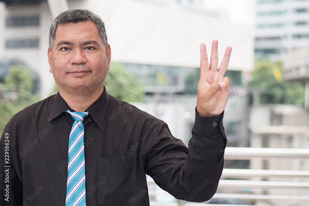 happy old man pointing up three fingers; retired pensioner counting, numbering with finger point; senior old man points three fingers up portrait; southeast old senior man model happy old man pointing up three fingers; retired pensioner counting, numbering with finger point; senior old man points three fingers up portrait; southeast old senior man model