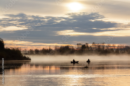 In the morning dawn, fishermen in boats on the water illuminated by the dawn throw gear into the water.